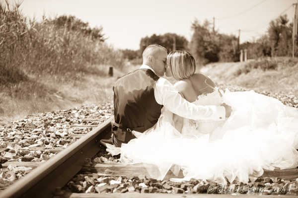 Photographie d'un couple de mariés assis sur une voie de chemin de fer réalisée par Huitièm'art, photographe à Avignon (Vaucluse)